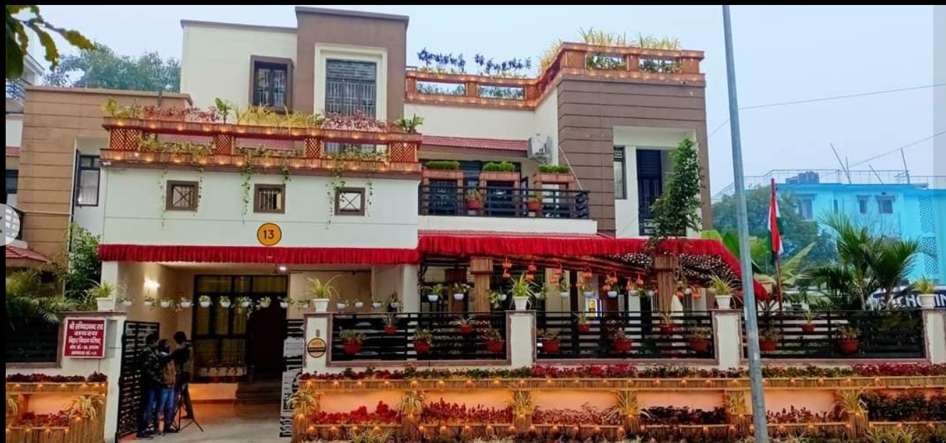 The facade now — bamboo planter railings on every floor, flowering plants cascading along the boundary, red valance detailing