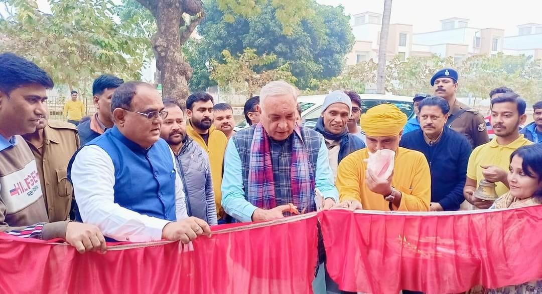 Inauguration ceremony — dignitaries cutting the red ribbon, surrounded by the crowd and security