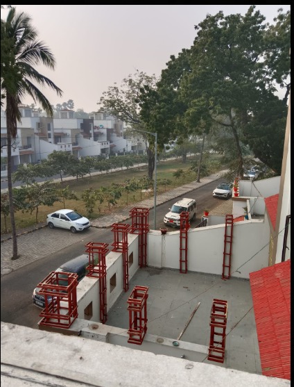 Red metal planter frames positioned along the boundary wall, viewed from the rooftop