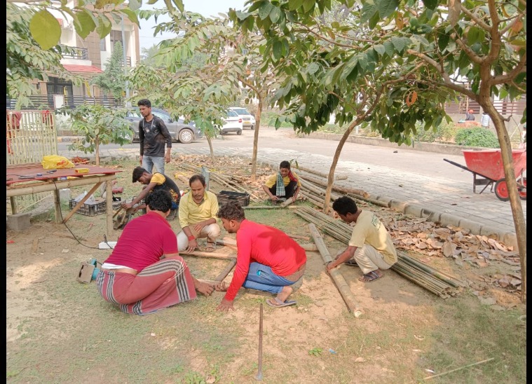 Six artisans sitting under trees, cutting and shaping bamboo poles by hand