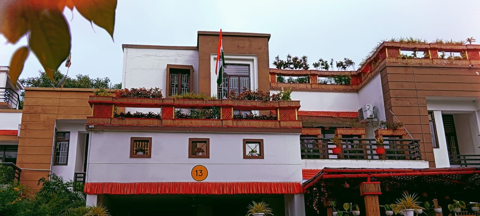 The completed Vatika in daylight — bamboo planter railings on every level, the Indian flag above, rooftop garden visible